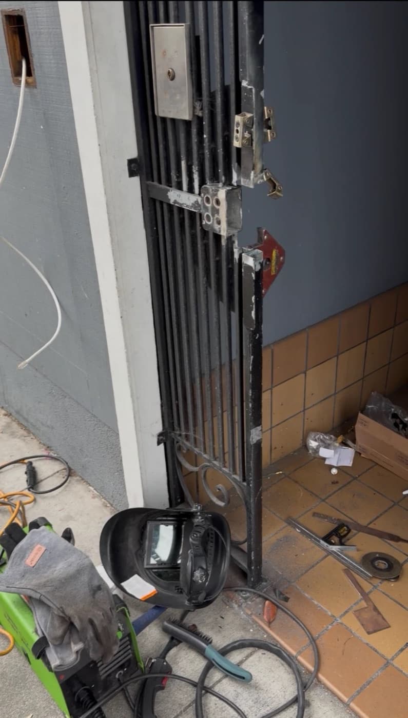 Welding a lock mount onto a gate on-site, with the welder and helmet