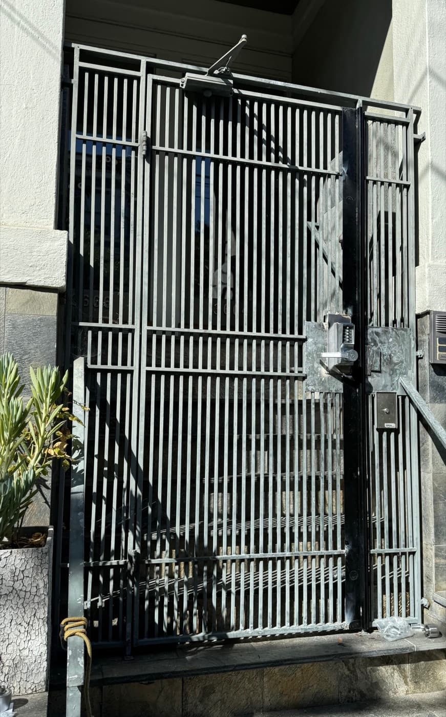Building entry gate with a heavy-duty closer and a keypad lock mounted on welded plates