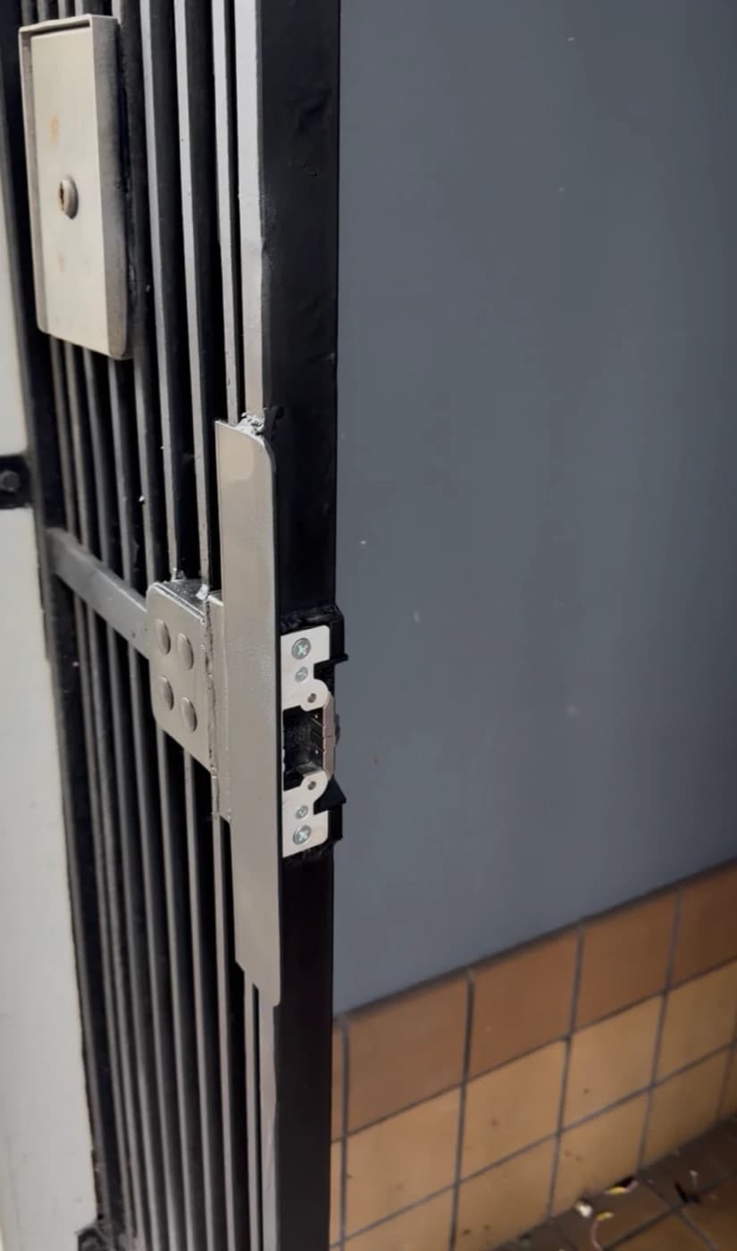 Interlocking latch guard and electric strike welded onto a steel entry gate