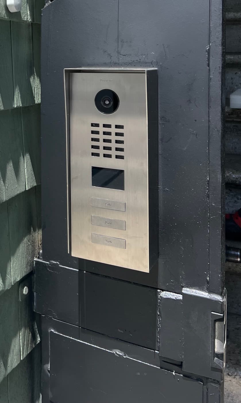 Video intercom panel set into a custom steel housing on a security gate