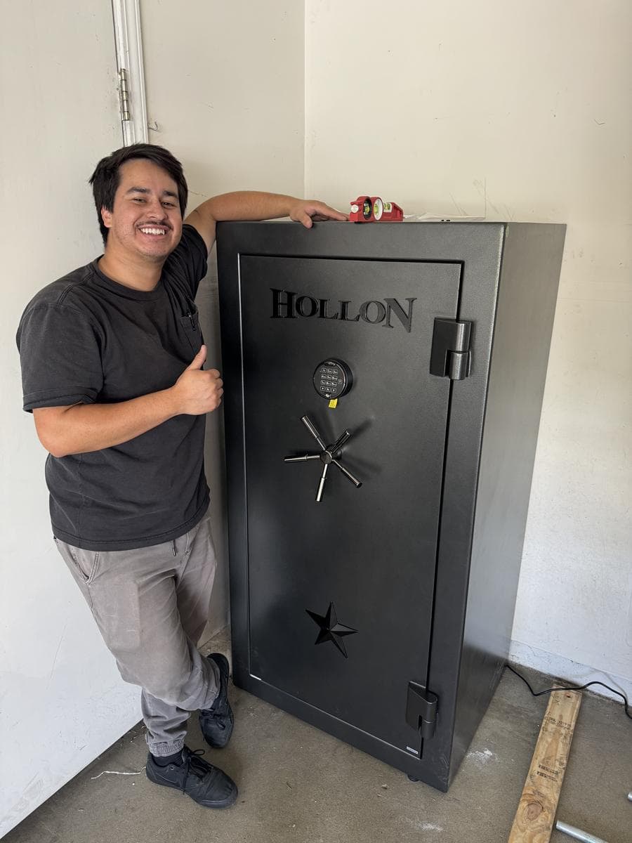B&B technician next to a newly installed black Hollon gun safe with a level on top