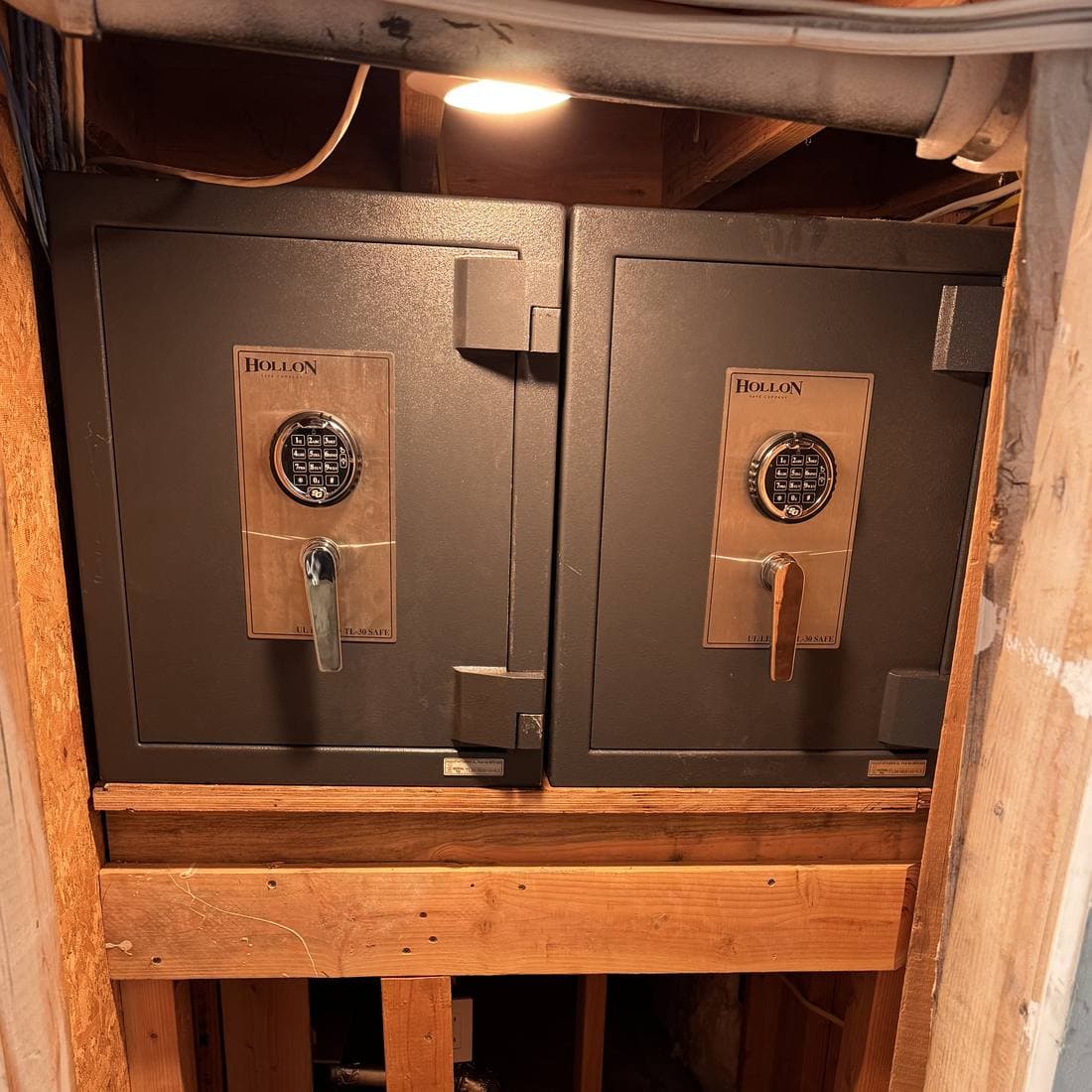 Two Hollon safes set side by side on a built platform inside a narrow security room in a new construction home